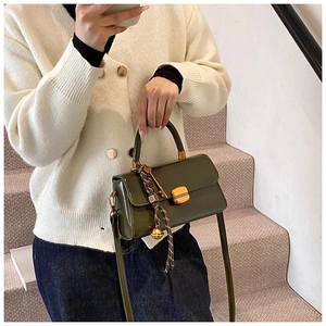 Detail of olive green leather handbag with gold buckle and woven rope ornament