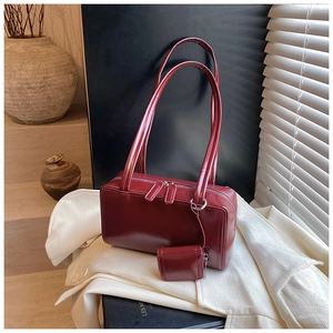 Detail of burgundy faux leather pillow bag showing the glossy finish and small matching pouch