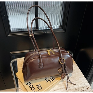 Close-up of vintage brown bowling bag with glossy leather and golden zipper detail