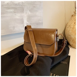 Detail view of vintage brown glossy leather square crossbody bag on a casual setting