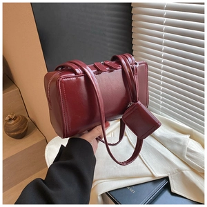 Detail of burgundy patent leather shoulder bag with matching mini bag and zipper closure