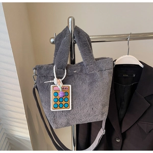 Close-up of soft grey plush tote bag with a playful yellow calculator charm accessory