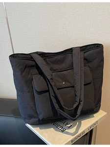 Large black quilted tote bag with front flap pocket for daily commuting and student use