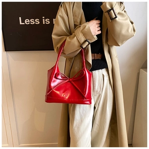 Détail d'un sac à main rouge en cuir verni avec nœud élégant et double poignée robuste