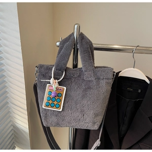 Detail of grey plush bucket bag with fuzzy texture and colorful calculator charm