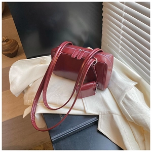 Close-up of wine red glossy faux leather pillow bag with a mini matching pouch