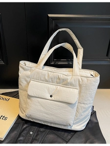 Quilted beige canvas tote bag with large front pocket and zipper on black leather