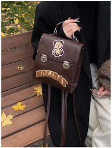 Close-up of vintage brown leather backpack with teddy bear and holiday patch details