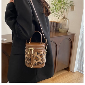Detalle de bolso tipo saco con estampado de leopardo, cuero marrón y remaches dorados