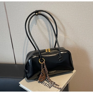 Detail of a black leather bowling shoulder bag with gold hardware and logo print