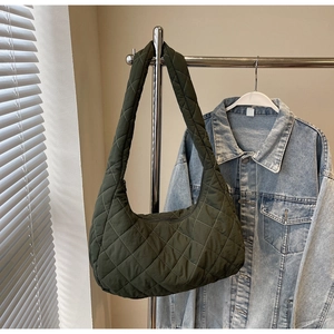 Detailed view of dark olive green quilted hobo bag hanging against a denim jacket