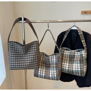 Drie getextureerde tweed shopper tassen met ruitpatronen op een metalen display
