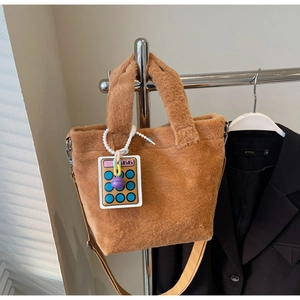 Detailed close-up of brown plush bucket bag with canvas strap and cute calculator charm