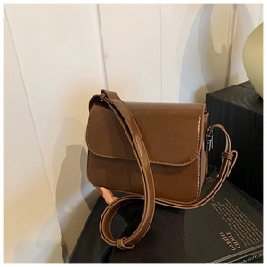 Detail of a caramel synthetic leather square bag with a flap cover and silver hardware