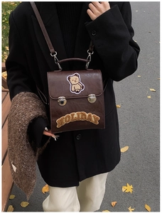 Detail of retro brown PU leather backpack with bear embroidery and metal buckle closure