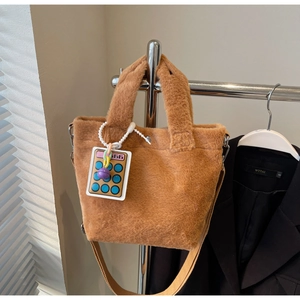Detail of soft brown faux fur tote with a calculator charm on a woven strap
