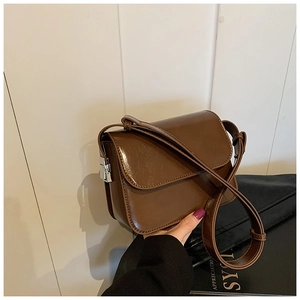 Detailed side view of brown PU leather crossbody bag with silver buckle and adjustable strap