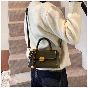 Detailansicht der moosgrünen Lackhandtasche mit Goldverschluss und Seidenschal