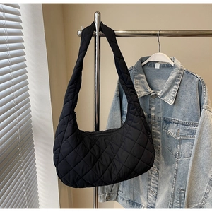 Detail of black quilted hobo bag with classic diamond stitching on a metal hanger