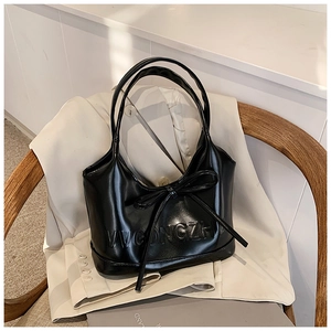 Détail du sac à main en cuir noir avec nœud décoratif et logo VVGONGZH embossé sur le devant