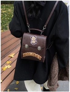 Detailed view of vintage dark brown backpack with plush bear patch and metal buckle