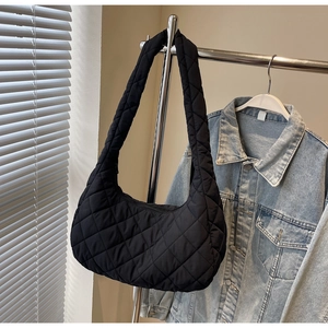 Detail of a black quilted crescent hobo bag made of glossy polyester fabric with wide strap