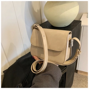 Detail of a minimalist cream rectangular crossbody bag with smooth faux leather texture