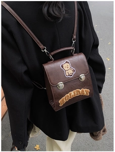 Rear view of a dark brown vintage backpack with bear patch and holiday embroidery on a coat