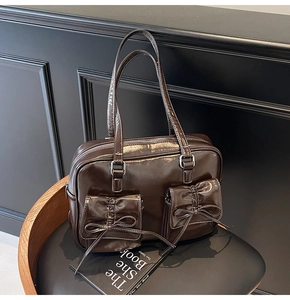 Detail of dark brown patent leather tote bag with bow-knot pockets and silver hardware