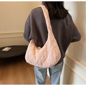 Detail of light pink quilted moon bag with wide shoulder strap worn by a model