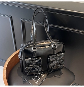 Detail of black faux leather tote bag with functional bow pockets and glossy finish