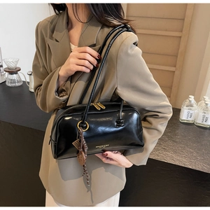 Detail of black glossy bowling bag with gold hardware and stylish charm accessories
