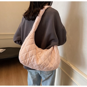 Detail of pink quilted tote bag with diamond pattern worn as a shoulder bag