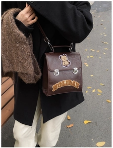 Detail of vintage dark brown faux leather bag with bear patch and embroidery