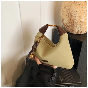 Détail du sac hobo en tissu vert avec poignée en cuir marron et boucle dorée