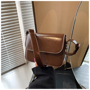 Detail view of a dark brown crossbody bag with a magnetic flap and adjustable strap