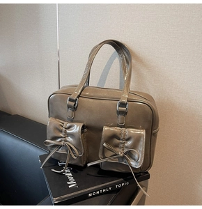 Detail of khaki tote bag featuring symmetrical front pockets and elegant bow decorations