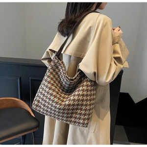Detail van een grote geruite tote bag met pied-de-poule patroon en leren hengsels op de schouder