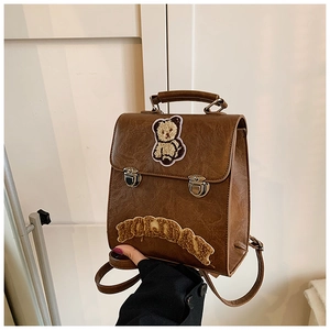 Detail of vintage dark brown backpack with plush bear embroidery and holiday patch logo