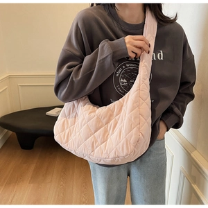 Detail of pink quilted hobo bag with padded nylon texture and wide shoulder strap