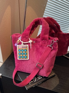 Fuchsia plush faux fur bucket bag with 666 charm and shoulder strap on book