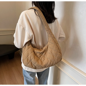 Brown quilted nylon hobo bag shown from the back on a model in a minimalist setting