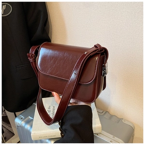 Detailed macro view of burgundy faux leather crossbody bag with vintage oil-wax texture