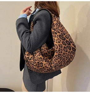 Close-up of a large leopard print hobo bag worn by a model in a grey suit