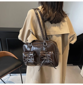 Detail of a coffee brown glossy leather tote featuring bow pockets and white contrast stitching