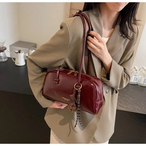 Detail of burgundy leather bowling bag with silver zipper and logo shown on shoulder