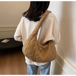 Brown quilted hobo bag styled as a shoulder bag on a model in a minimalist room