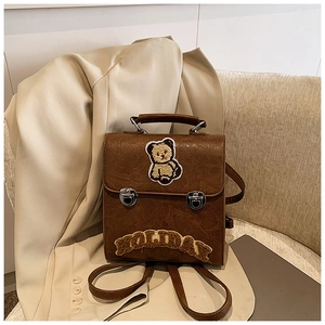 Detail of vintage brown leather backpack with teddy bear patch and HOLIDAY embroidery