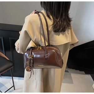 Close-up of shiny dark brown shoulder bag with gold zipper and woven rope detail