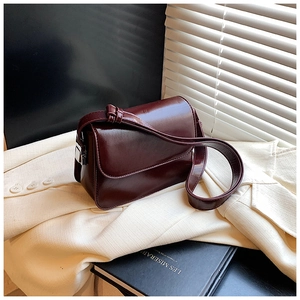Detail of burgundy glossy PU leather square bag with silver hardware and knotted strap